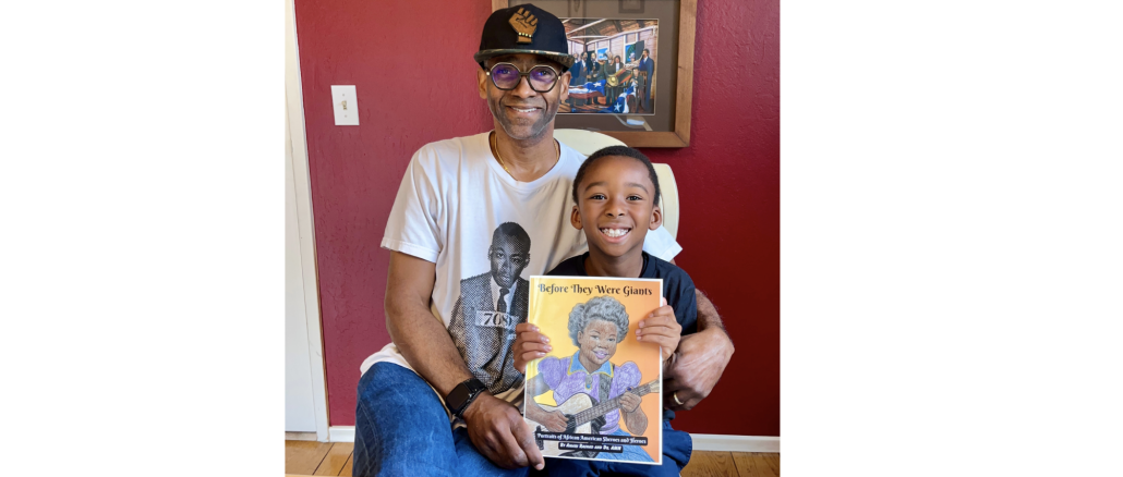 A Black father wearing baseball cap holds a coloring book with his son